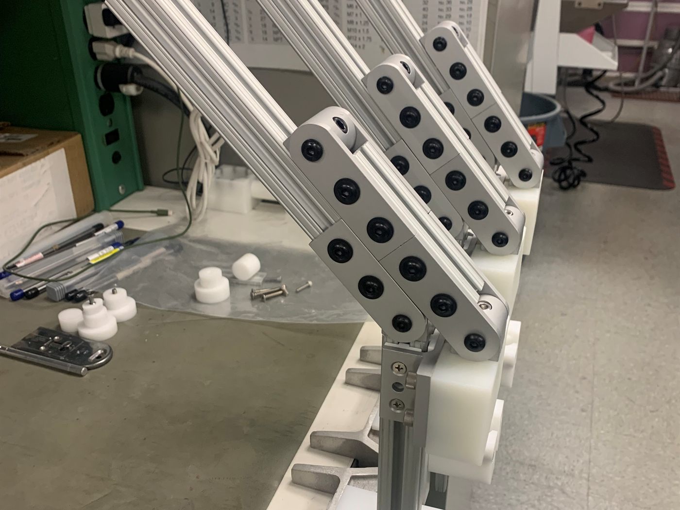 Three-station syringe press fixture built from machined aluminum arms, extrusion, and white plastic blocks